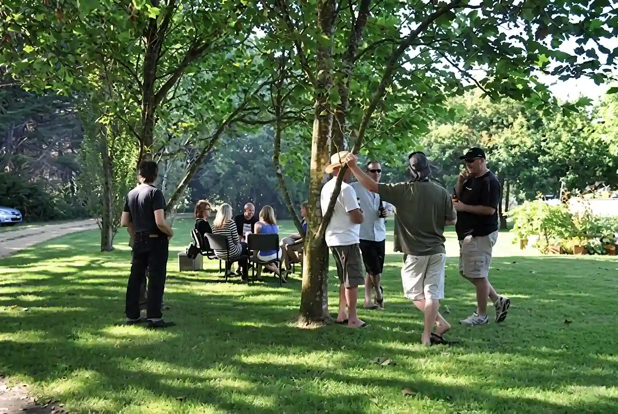 Small groups of people relaxing under the trees in the garden of Butterfly Farm bed and breakfast.