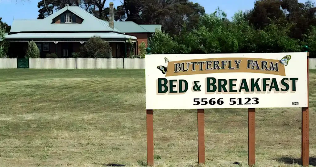 the front of Butterfly farm homestead in the background, with the large Butterfly Farm Bed and Breakfast sign in the foreground.