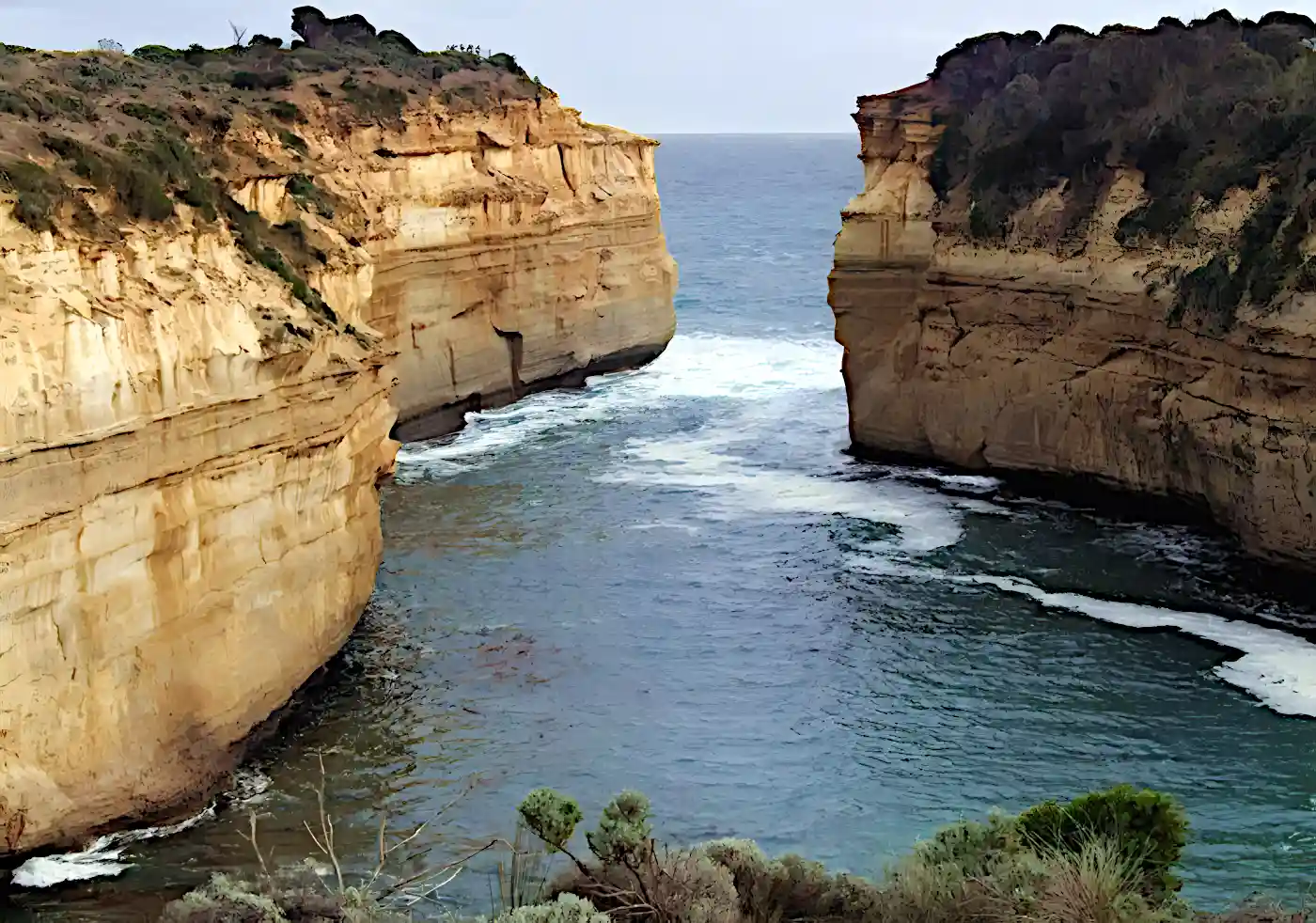 Loch Ard Gorge on the Great Ocean Road. The sea is calm between the high vertical cliffs of the Gorge.